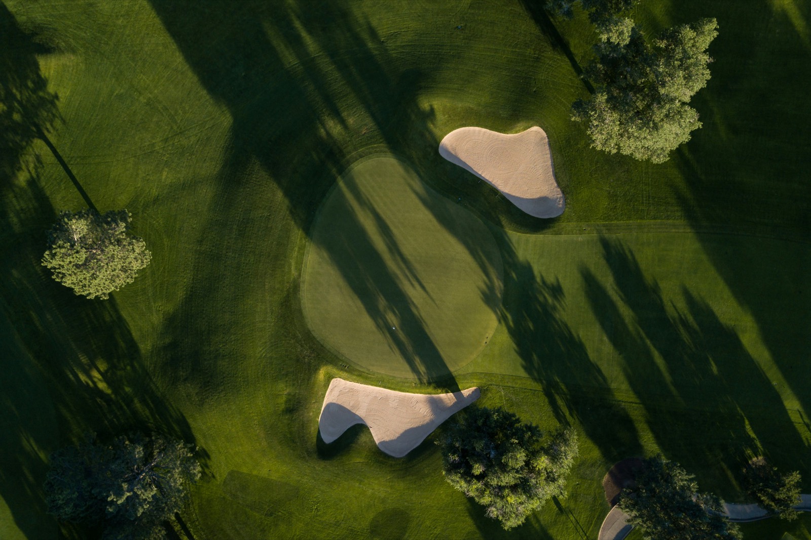 Aerial view of a golf green flanked by sand bunkers.
